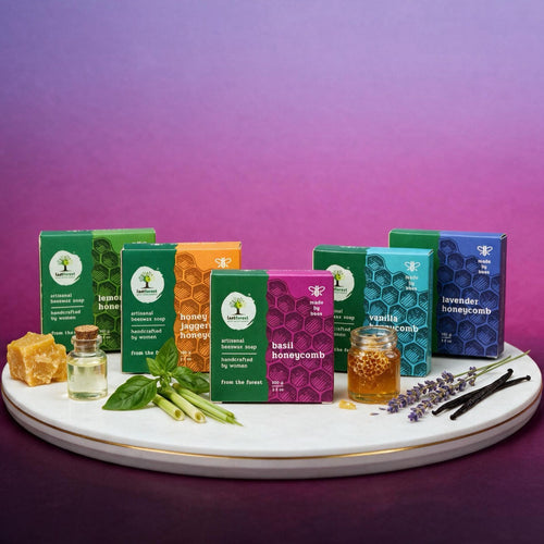 A collection of artisanal herbal soaps in colorful boxes arranged on a white marble tray with natural ingredients like honeycomb, fresh basil, lavender, and vanilla beans, set against a purple gradient background.