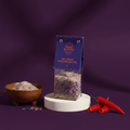 Bhutan Blossoms Himalayan Salt Mix packaging with a bowl of salt and red peppers on a purple background